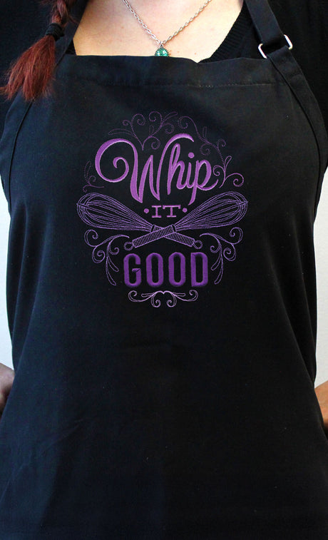 Black apron with 'Whip It Good' machine embroidery design worn by a person.
