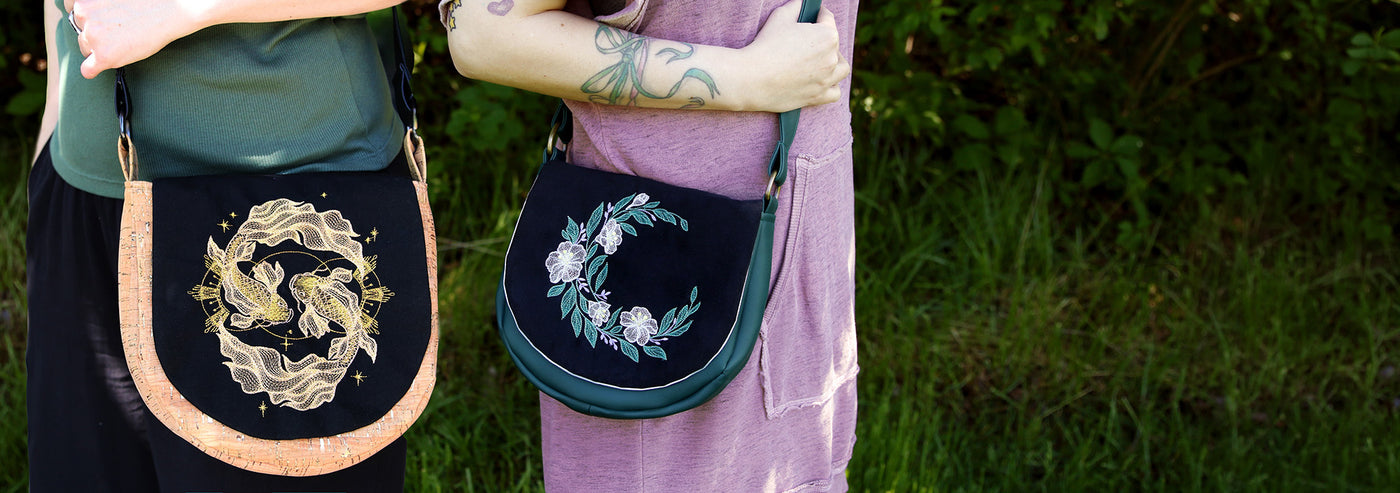 Two machine embroidered handbags held by people against a natural background.