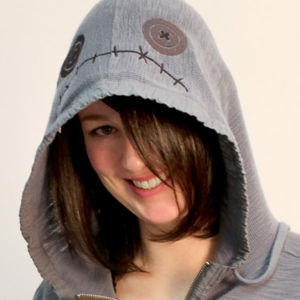 Close-up of a hoodie with stitched facial features and a mouth, shown as a digitally downloadable machine embroidery design.