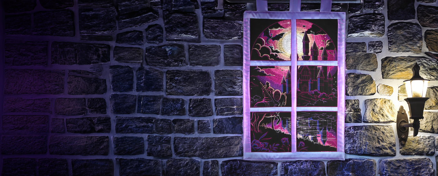 Machine embroidered wall hanging of a fantasy scene hanging on a stone wall.