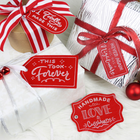 Gift tags reading Crafted with Attitude displayed on gift boxes, showing the embroidered text design.