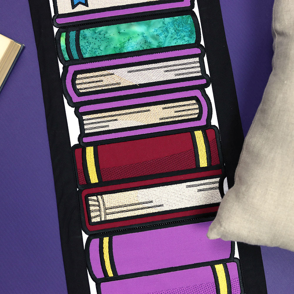 Digitally downloadable machine embroidery Design Pack showing embroidered illustrated books in purple and beige tones.
