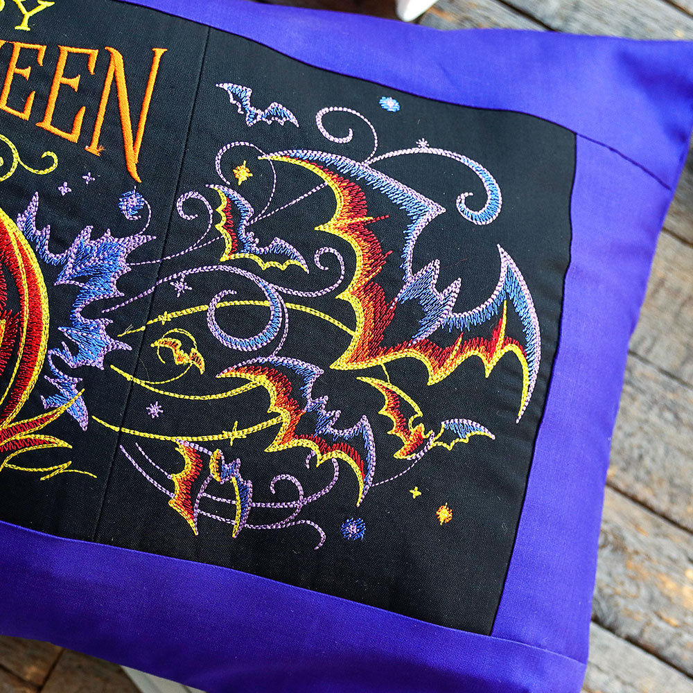 Embroidery design shows jack-o-lanterns, bats, and a blue border, as a digitally downloadable machine embroidery design.