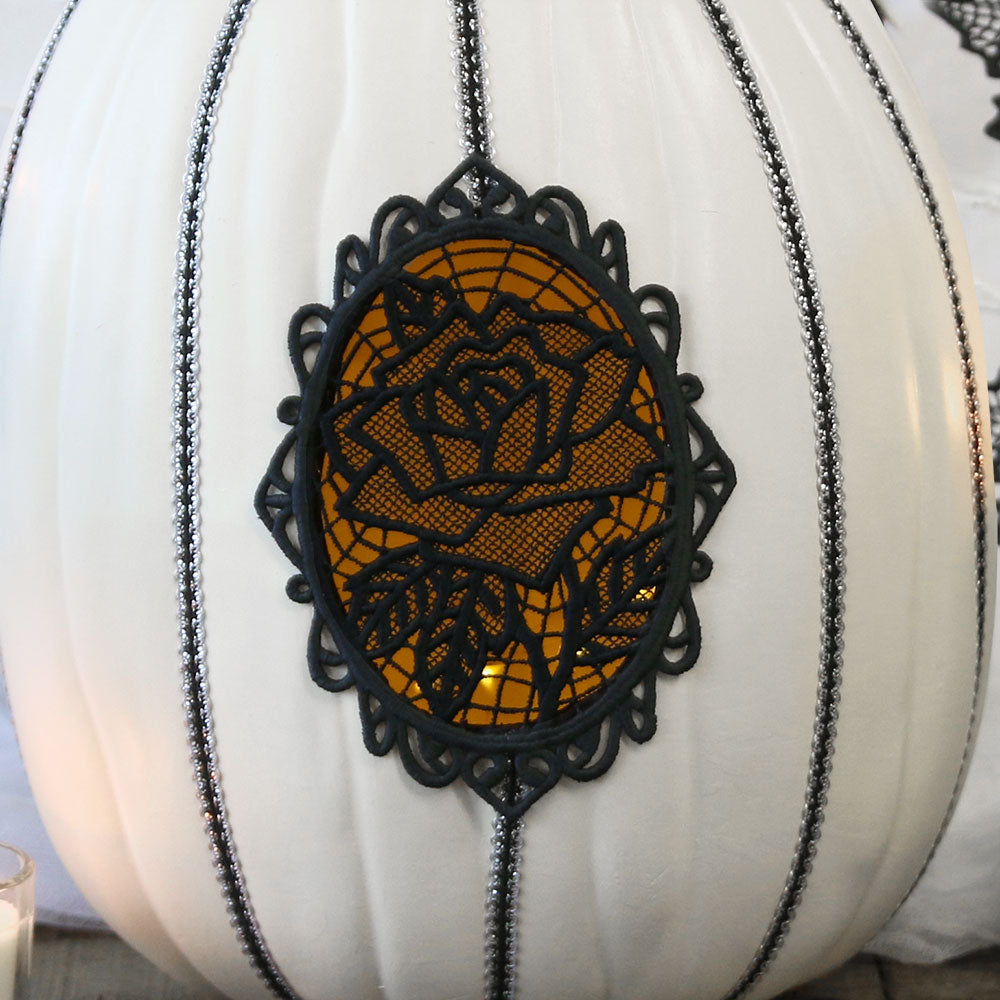 Digitally downloadable machine embroidery design of a white pumpkin with black glitter accents and a lace rose motif.