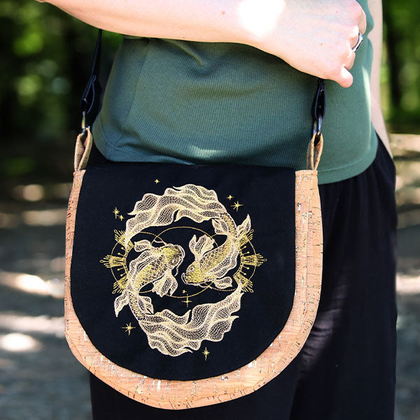 Gold koi and wave embroidery in metallic thread, shown on purse surface, with light highlighting the stitched details.