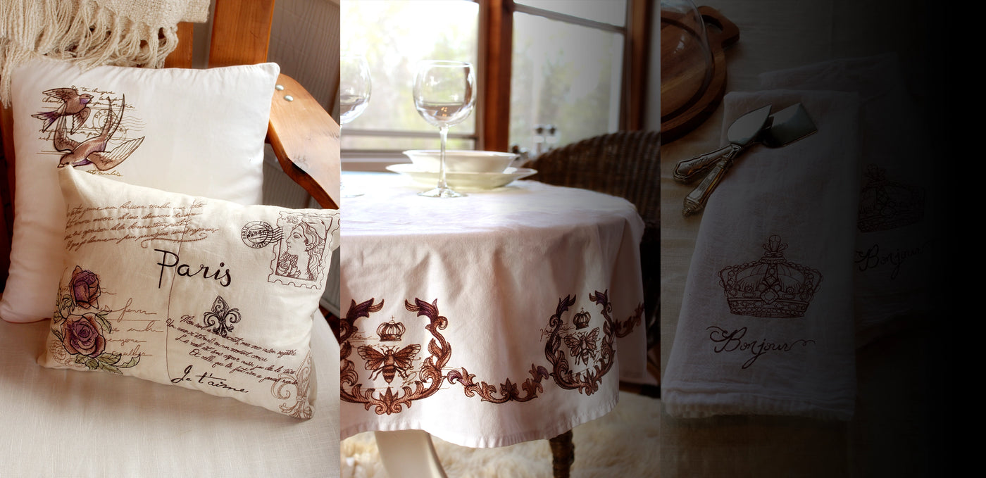 Machine embroidery Parisian-inspired designs on white pillows, table cloth, and towel.