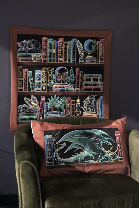 Decorative pillow with embroidered design of a dragon on a green armchair next to the build a bookshelf panel scene