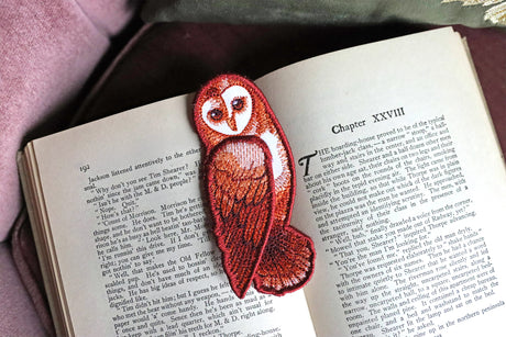 Machine embroidered freestanding owl bookmark resting on a book