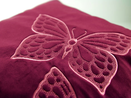 Close up of a machine embroidered embossed butterfly on purple fabric