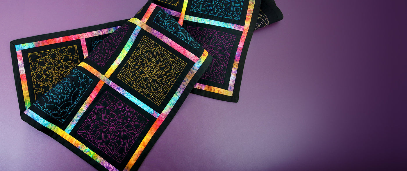 Colorful quilted fabric with geometric patterns on a purple background