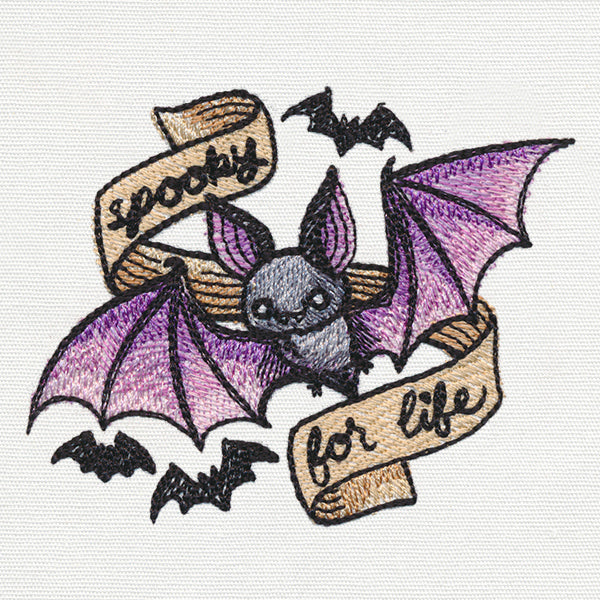 Embroidery design of a bat with purple wings, smaller bats, and a “spooky for life” banner in stitched lettering.
