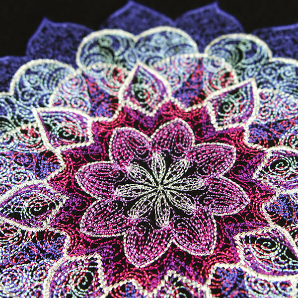 Intricate purple, pink, and white mandala embroidery with sheer stitching accents on a dark background.