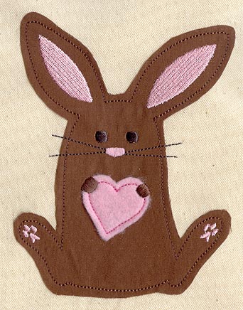 Brown bunny applique with pink inner ears and a heart-shaped belly on beige fabric, digitally downloadable embroidery design.