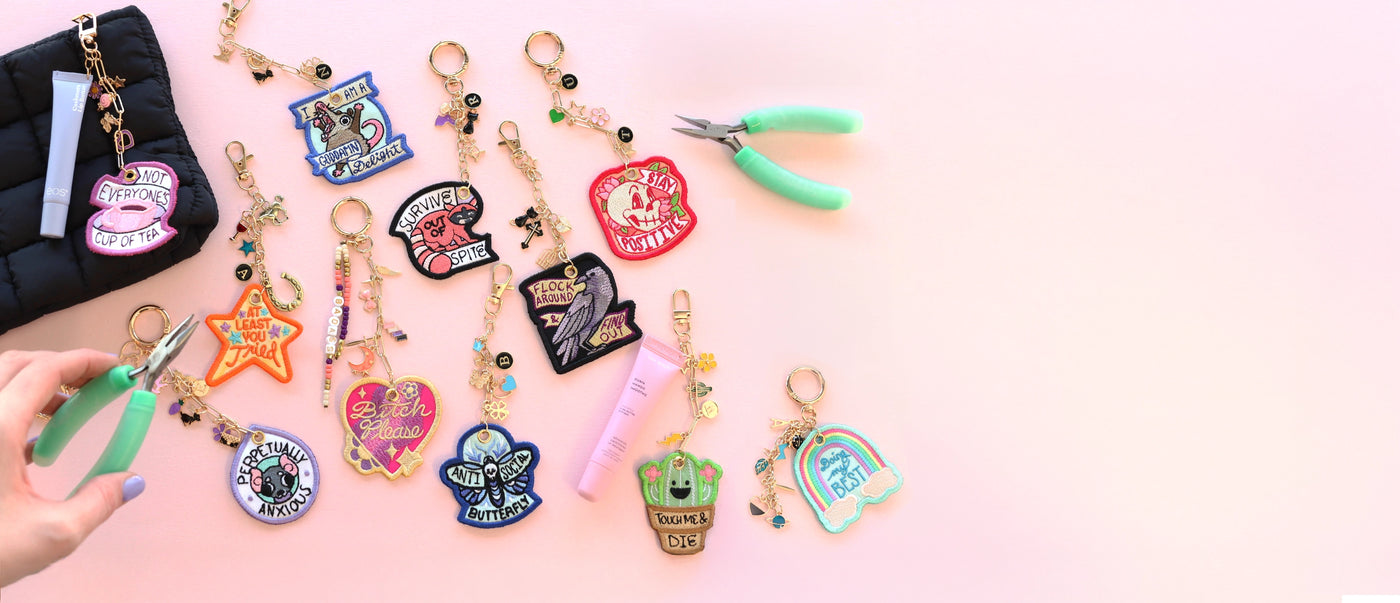 Colorful machine embroidery keychain designs with charms on a pink background
