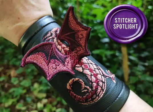 A machine embroidery 3D dragon design on a black cuff with a person wearing it.