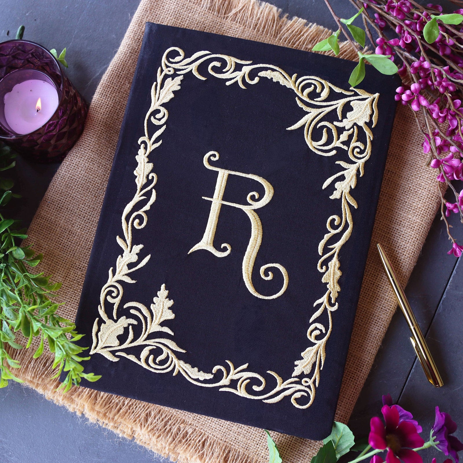 an embroidered journal cover with a blank frame design and a letter monogram in the center