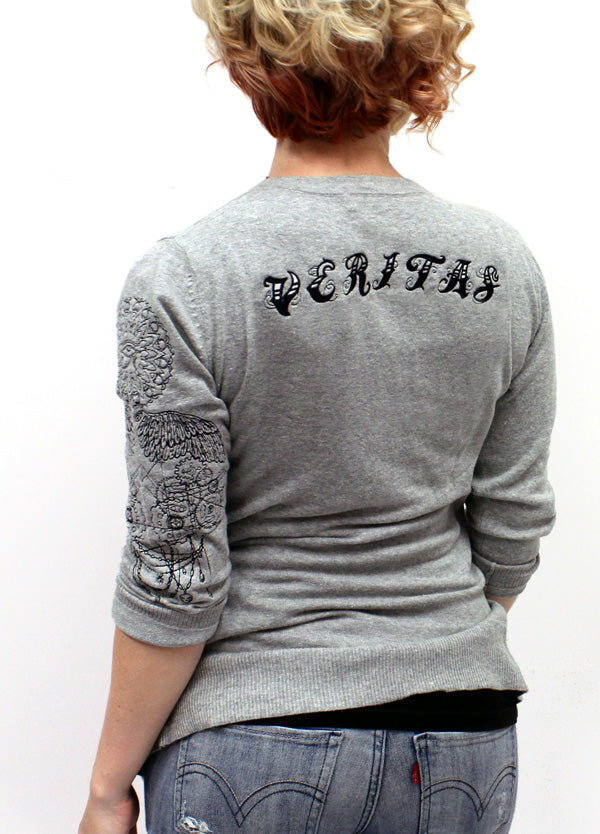 woman modeling top featuring embroidered Inked Alphabet, Light as Air, Eye of Ra Medallion, Blueprint Cogs and Spooky Drape designs