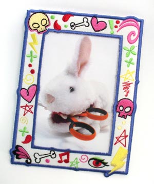 Completed embroidered photo frame project, featuring Doodle Frame (In-the-Hoop) design and a photo of a plush rabbit holding a pair of shears