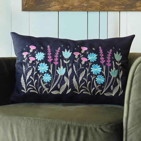 Square pillow with intricate blue, purple, and pink wildflower embroidery; a digitally downloadable design is shown.