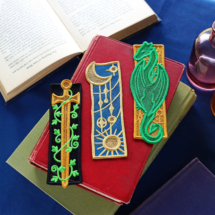 Freestanding lace bookmarks - a sword, celestial and dragon on top of books