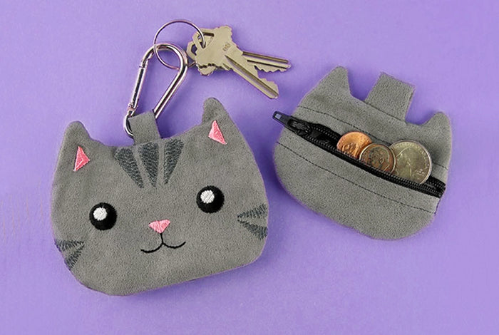 Machine embroidered cat zipper pound with coins inside on purple background.