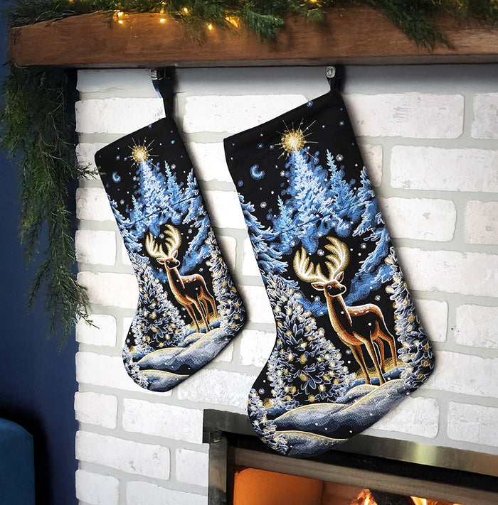 Two machine embroidered Christmas stockings with a winter deer scene hanging from a fireplace