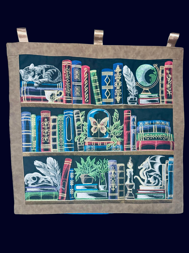 Machine embroidery bookshelf panel designs hanging on a wall.