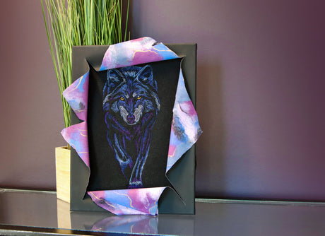 Framed artwork of machine embroidered wolf with colorful abstract design on a dark background