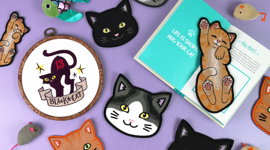 Collection of machine embroidered cat-themed designs on a purple background