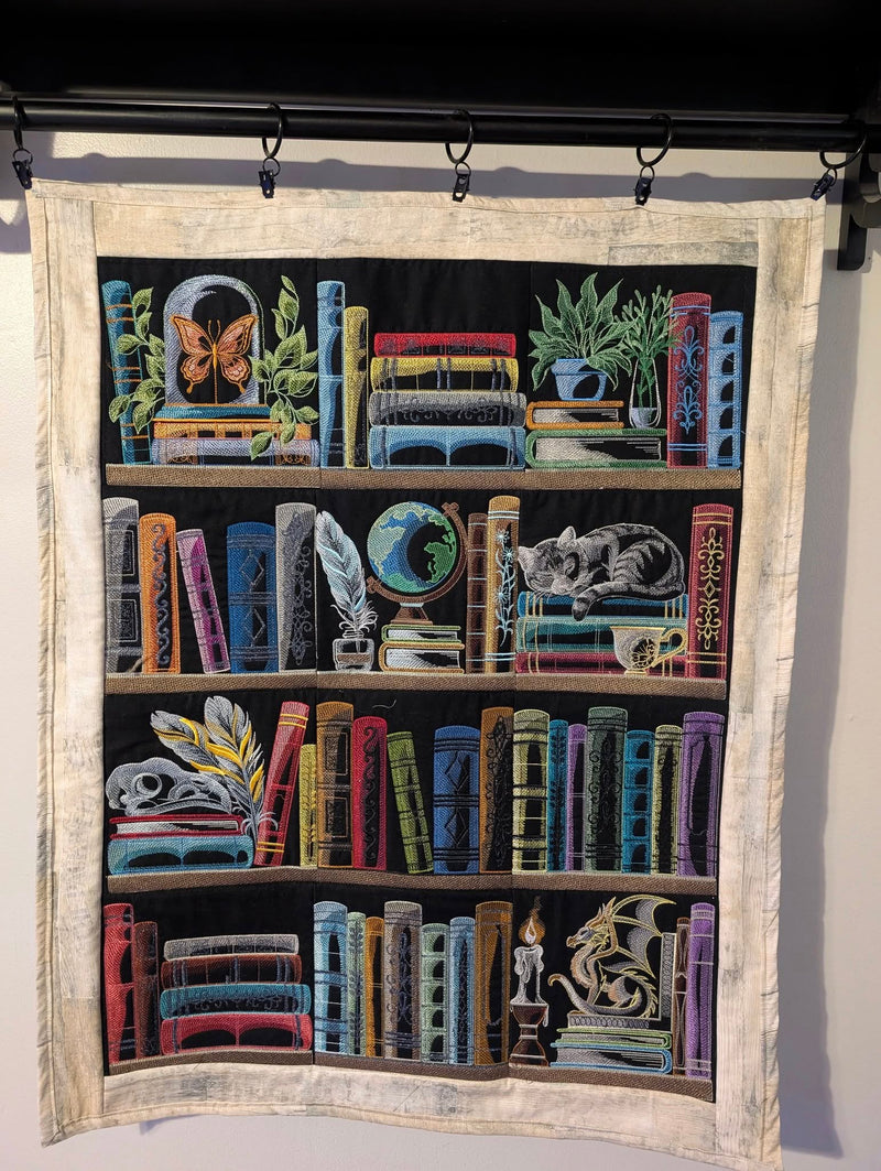 Machine embroidery bookshelf panel designs hanging on a wall.
