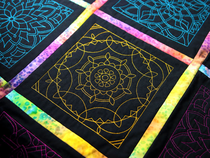 Colorful quilt with machine embroidery geometric patterns on a black quilt 