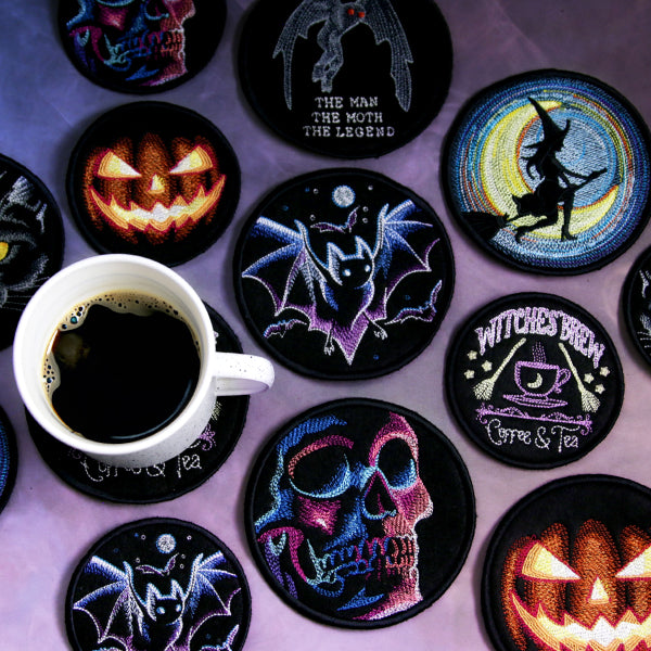 Set of Halloween-themed machine embroidered coasters with a cup of coffee on a matching coaster.