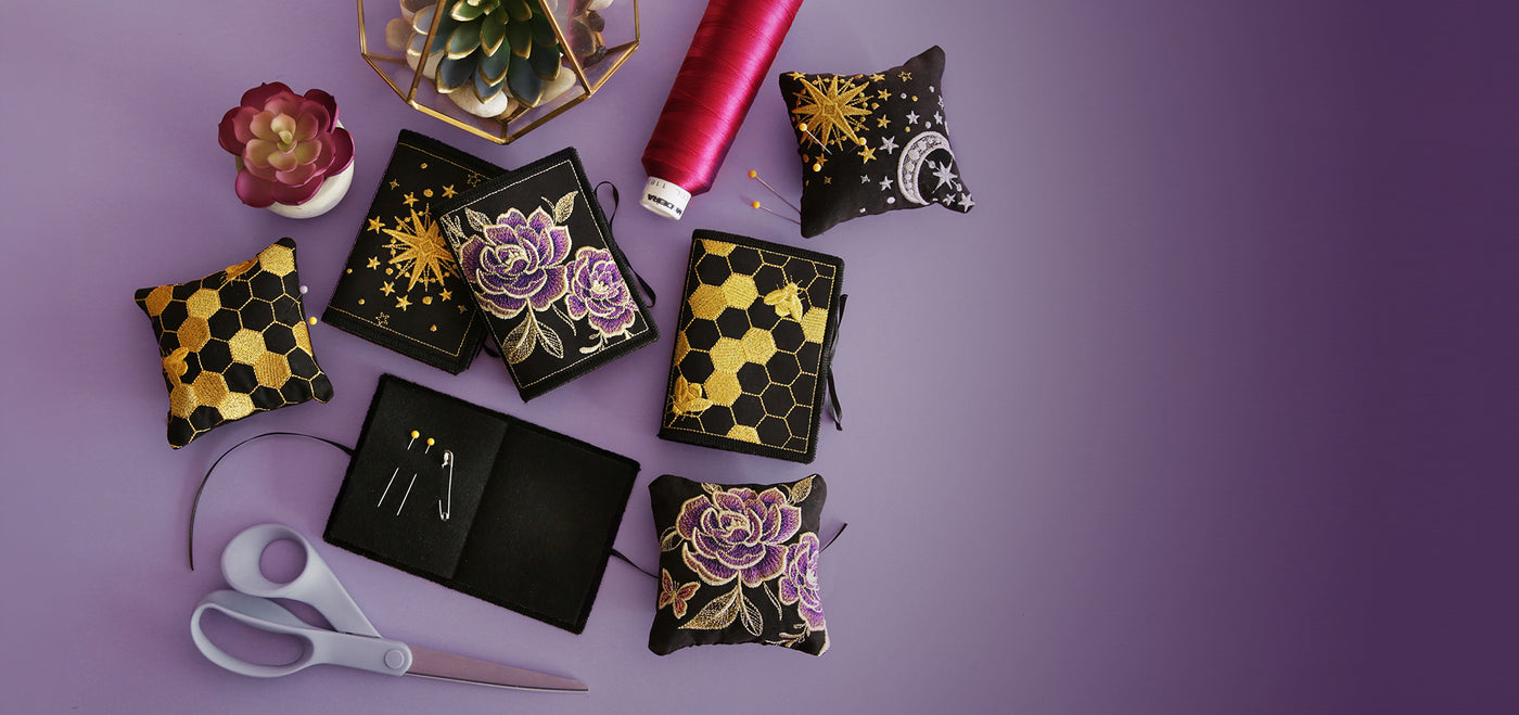 Machine embroidery needlebook and pincushion designs on a purple background.