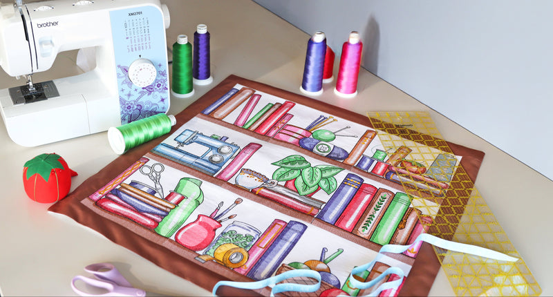 Machine embroidery bookshelf designs surrounded by thread and a sewing machine.