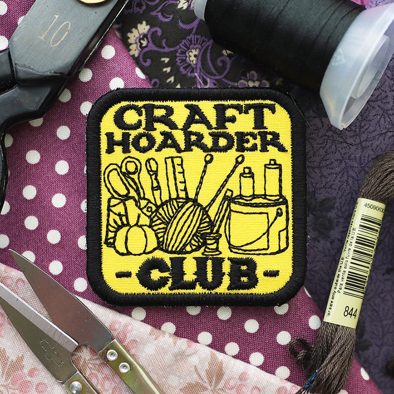 Patch with 'Craft Hoarder Club' design on a polka dot fabric background with sewing supplies.
