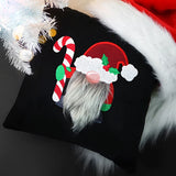 Black fabric with an embroidered gnome wearing a red Santa hat with holly, a faux gray beard, holding a red and white candy cane, next to white tree branches.