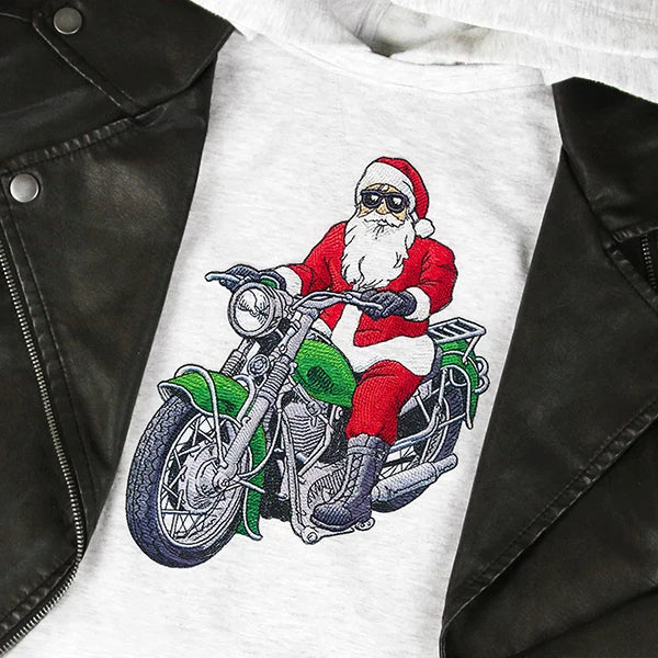 Embroidery of Santa Claus wearing sunglasses and riding a green motorcycle on a light gray fabric, partially covered by a black leather jacket.