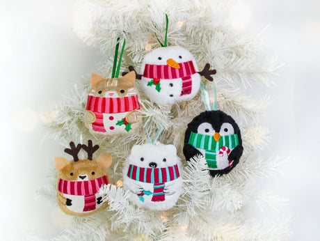 Set of four machine embroidery Christmas ornaments shaped like a snowman, penguin, bear, and deer, each wearing a red and green scarf, on a white background.