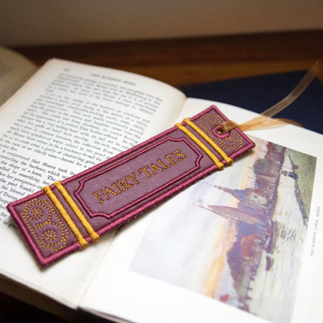 Machine embroidery in-the-hoop bookmark with 'FAIRY TALES' text on an open book