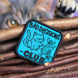 Machine embroidery in-the-hoop patch with text 'Bad Decisions Club' by wood sticks.