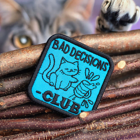 Machine embroidery in-the-hoop patch with text 'Bad Decisions Club' by wood sticks.