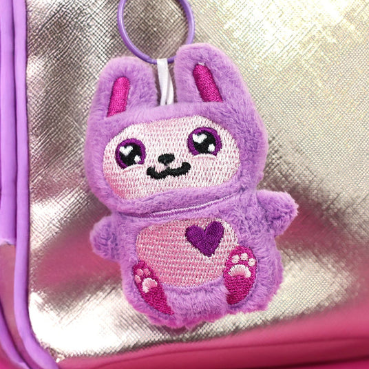 Machine embroidery in-the-hoop bun on a keychain in front of a purse