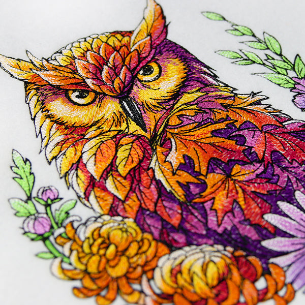 Colorful owl machine embroidery with floral elements on a white background