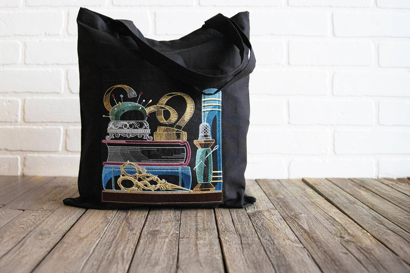 Black tote bag with bookshelf machine embroidery design on a wooden surface and white brick wall background