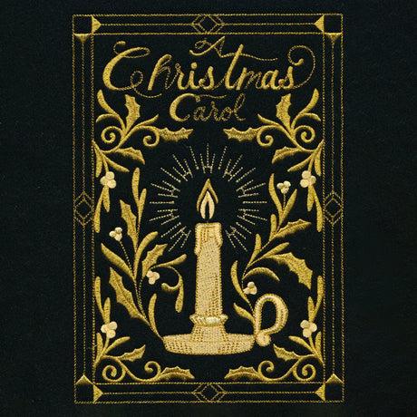 Gold embroidery on black fabric shows a candle in a holder surrounded by holly leaves and berries with the text "A Christmas Carol" framed by decorative borders.
