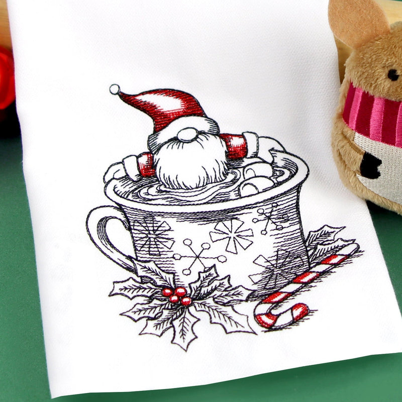 Tea towel with a machine embroidery Christmas design of a gnome in a mug on a green background