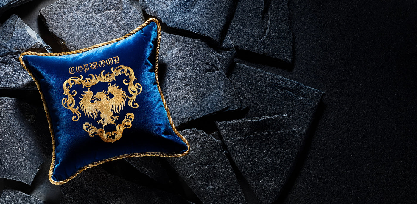 Blue pillow with gold embroidery on a dark stone surface
