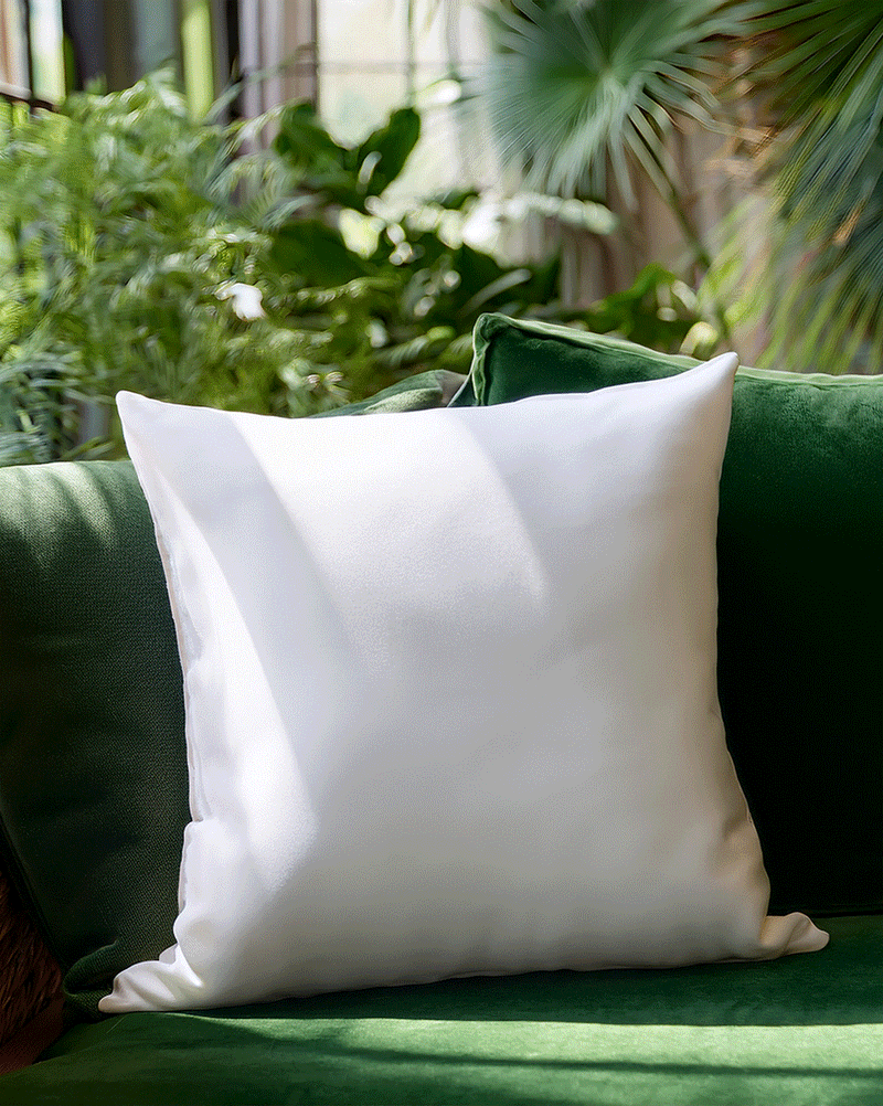 Machine embroidery butterfly designs interchanging on a white pillow against a green couch.