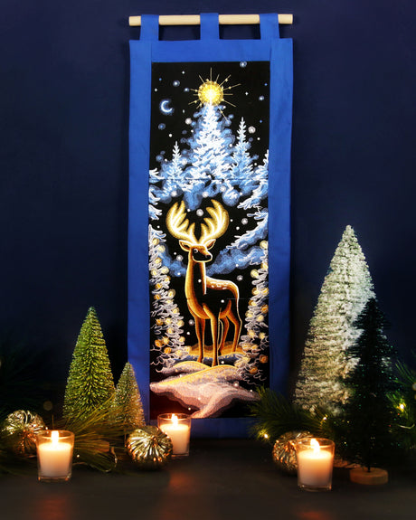 Machine embroidery winter panel scene design, surrounded by candles and small trees on a dark background.