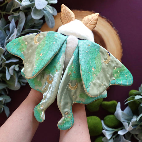 3D machine embroidered plush moth in someone's hands against a purple background